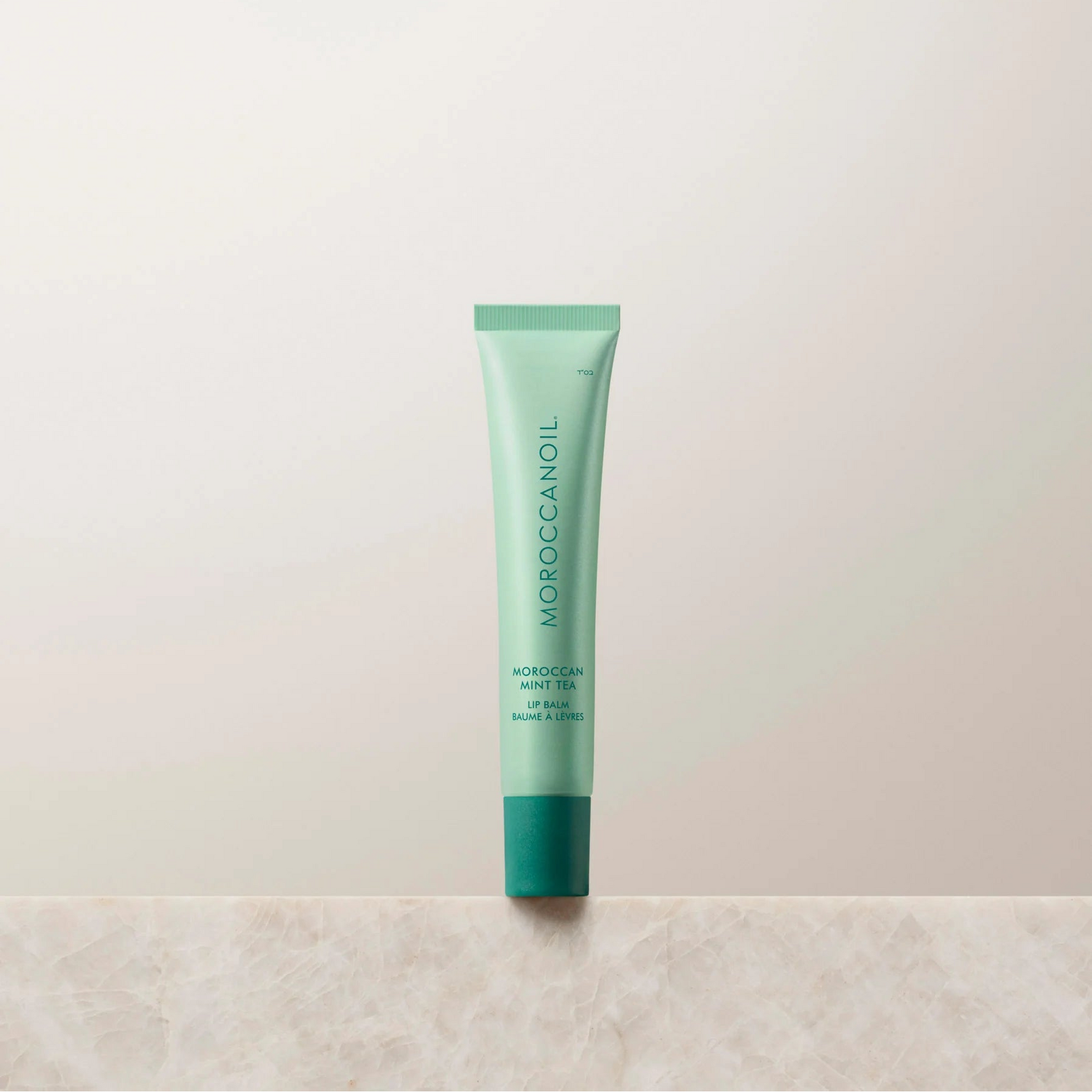 Green lip balm tube on a light beige background