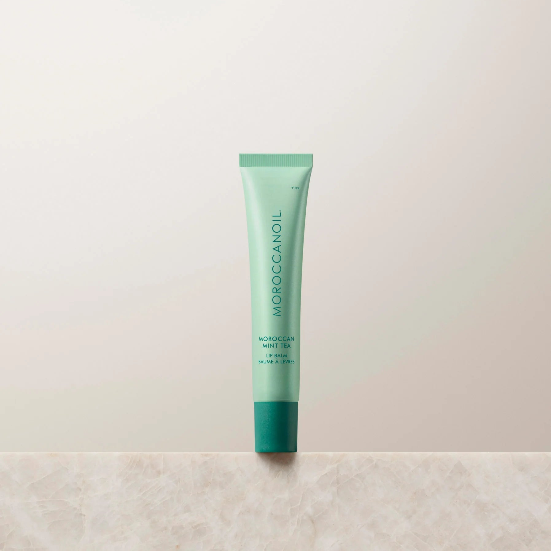 Green lip balm tube on a light beige background